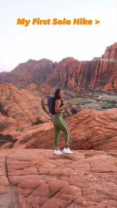 a woman standing on top of a red rock covered hillside with her back to the camera