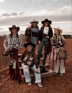 a group of people standing next to each other on top of a wooden bench in the middle of a dirt field