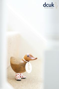 a small wooden duck figurine holding a tag