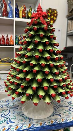 a green and red christmas tree on top of a table with other items in the background