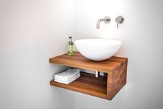 a bathroom sink with a wooden shelf underneath it and a white bowl on the counter