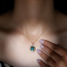 a woman wearing a necklace with an emerald stone