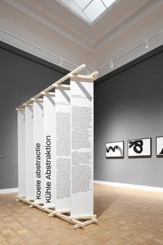 an art gallery with three large white columns in the center and two black and white pictures on the wall