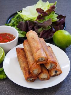 vietnamese fried spring rolls on a plate with dipping sauce and lettuce next to it