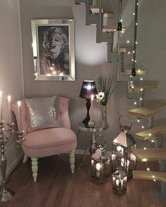 a pink chair sitting next to a stair case filled with candles and other decor on top of a hard wood floor