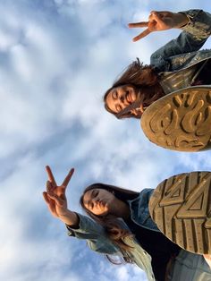 two women standing next to each other with their fingers in the air