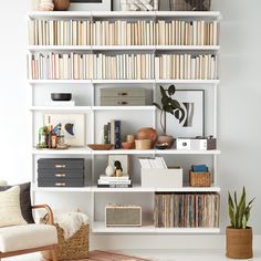 a living room filled with lots of books on top of a white book shelf next to a chair