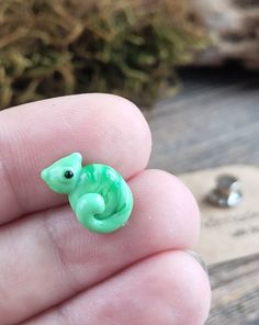 a small green toy animal sitting on top of a persons finger