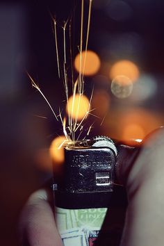 a person holding a lighter in their hand with some sparklers coming out of it