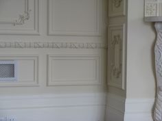 the corner of a room with white walls and decorative moldings