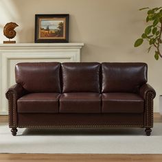 a brown leather couch sitting on top of a white rug in front of a fireplace