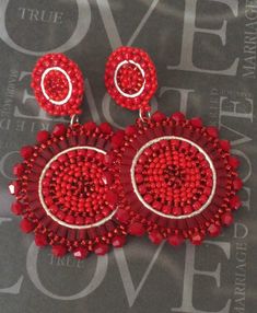 two pairs of red beaded earrings on top of a black table with grey background