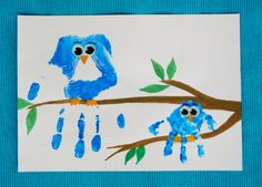 two blue birds are sitting on a tree branch with handprints in the background