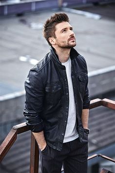 a man in black jacket and white t - shirt standing next to some railings