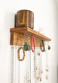 a wooden shelf filled with lots of necklaces and bracelets hanging from it's sides