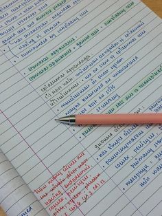 a pink pen sitting on top of a paper with writing in english and latin letters