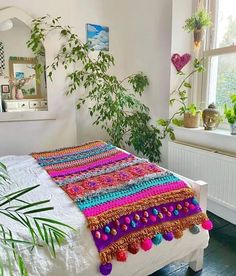 an instagram photo of a bed with colorful crochet and pom - poms