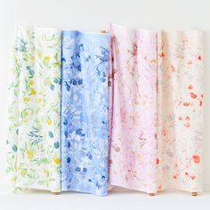 four different colored floral designs are lined up on a white surface, one is blue and the other is pink