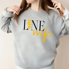 If you are looking for the perfect Lineman Wife Crewneck, Line Wife Sweatshirt, Cute Line Wife Crew, Lineman Wife Sweatshirt, Line Wife Sparks Fly Crew or Gift for Line Wife, then look no further! Made with a medium-heavy fabric blend of 50% cotton and 50% polyester (8.0 oz/yd² (271.25 g/m this sweatshirt feels cozy and is the perfect choice for those colder months. The classic fit along with the crew neckline deliver a comfy wearing experience with a clean-cut style. Meanwhile, the double-needle stitching at the shoulder, armhole, neck, waistband, and cuff seams add top-tier durability.  Say goodbye to itchiness thanks to the gray, pearlized tear-away label.  Made using 100% ethically grown US cotton. Gildan is also a proud member of the US Cotton Trust Protocol ensuring ethical and susta Bride Sweater, Funny Wife Shirts, Wife Sweatshirt, Wifey Sweatshirt, Mrs Sweatshirt, Bride Sweatshirt, Wife Humor, Sparks Fly