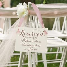 a sign that says reserved on the back of a white folding chair with pink ribbon