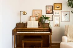 a living room with a piano, couch and pictures on the wall above it in various frames