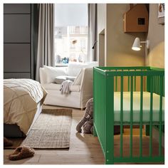 a baby's room with a green crib next to a white couch and chair