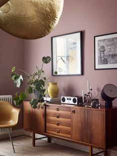 a living room with purple walls and wooden furniture, including a plant on the sideboard