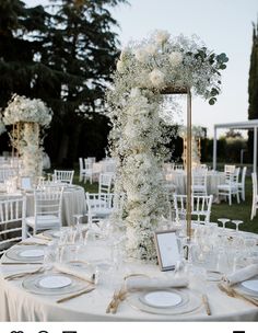 the table is set up with white flowers and place settings for guests to sit at