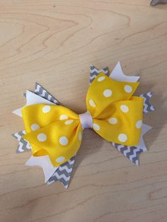 a yellow and gray bow with white polka dots on the top, sitting on a wooden surface