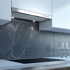 a kitchen with marble counter tops and stainless steel hood over the stove top is filled with wine glasses