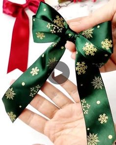 someone is holding a green ribbon with gold snowflakes on it and red bows