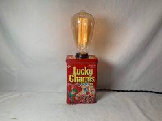 Unique lamp for desk, home, kitchen,  or just about anywhere a cool looking lamp is needed!  Can is in good shape, but shows some wear consistent with its age. A very nice repurposed item, and a great gift! Four different cereal cans available. Date on bottom of can is 1994. Cans have  artwork all around can. These  cans have  a touch sensor built in with 3 brightness levels that correspond with simply touching the can anywhere (see pictures and video). Has a black cloth covered power cord as seen, and a vintage-style squirrel-cage bulb, 60 watt. Also included is an antique style plug. Can is 5 inches high, and approx 10 inches high with bulb. Makes a great gift, and is ready to ship in about a week. Foothills Collective is a group of makers and artisans from the foothills of Northeastern Lamp For Desk, Kitchen Lamp, Zanesville Ohio, Cocoa Puffs, Lamp Kitchen, Squirrel Cage, Unique Lamp, Globe Lamps, Salt Lamps