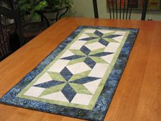 a wooden table with a blue and green quilted runner on it's edge