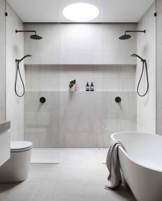 a bathroom with a white bathtub, toilet and shower head mounted to the wall