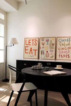 a dining room table with chairs and artwork on the wall above it that says let's eat