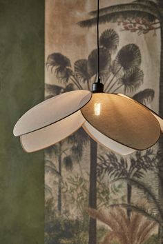 a light fixture hanging from a ceiling in front of a wall with palm trees on it