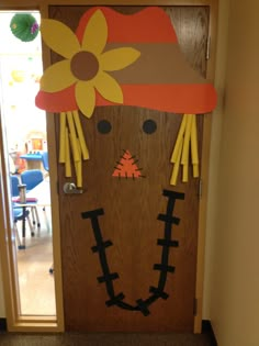 a door decorated to look like a scarecrow with a hat and flowers on it