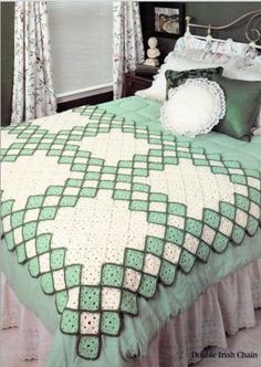 a crocheted bedspread on a bed with pillows