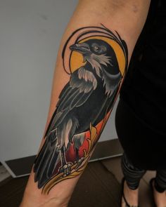 a black bird sitting on top of a person's arm with an orange circle around it