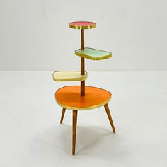 three tiered table with orange and green plates on each shelf, against a white background