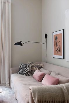 a living room with a couch, lamp and pictures on the wall in it's corner