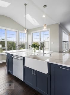 a kitchen with blue cabinets and white counter tops, an island style sink and dishwasher