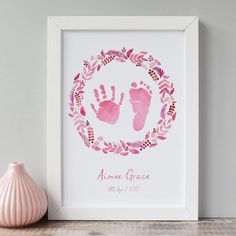 a baby's hand and foot print on a shelf next to a pink vase