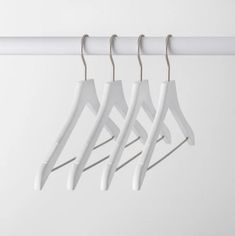 four white clothes hangers on a white wall