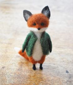 a small stuffed fox wearing a green sweater