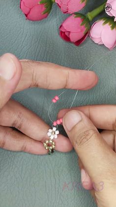 someone is sewing something with pink and white beads