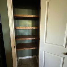 an empty pantry with shelves in the corner and tile flooring on the ground next to it