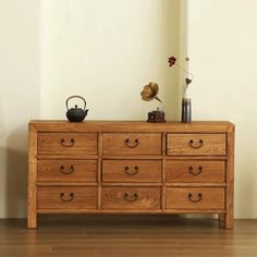 a wooden dresser sitting on top of a hard wood floor next to a white wall