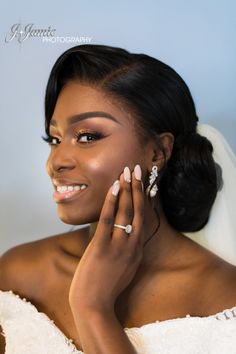 a woman in a wedding dress holding her hand up to her face and smiling at the camera