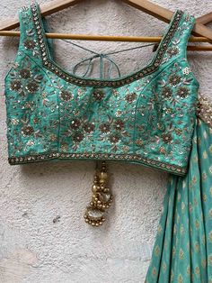 A three-piece jade green zari lehenga set from the Priti Sahni collection. This beautiful georgette small butti green lehenga with a heavy border of sequin, pearl and zari work detail with green accent is paired with a raw silk green blouse with sequin and zardosi embroidery detail all over. The lehenga has side hanging ball tassels to the waistline. And the blouse has a sequins tassel tie-up at the back. This outfit is completed with a sequin tulle dupatta with jade green accent in net material Navratri Green Embellished Lehenga, Green Embellished Lehenga For Navratri, Embellished Green Lehenga For Navratri, Bollywood Style Embellished Green Anarkali Set, Green Embellished Sets For Navratri, Green Embellished Traditional Wear For Navratri, Embellished Green Traditional Wear For Navratri, Embellished Green Georgette Anarkali Set, Pista Green Choli With Gota Work In Traditional Drape